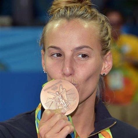 A Woman Holding Up A Gold Medal In Front Of Her Face