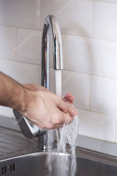 Un Hombre Se Lava Las Manos Con Agua Corriente Contra Una Pared Blanca