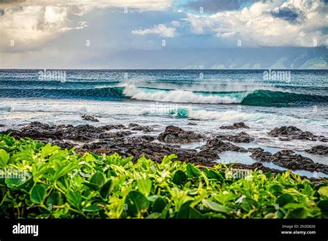 Waves Roll Into The Beach Of A Hawaiian Island With Lava Rock And