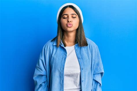 Joven mujer latina con un lindo gorro de lana mirando a la cámara lanzando un beso al aire