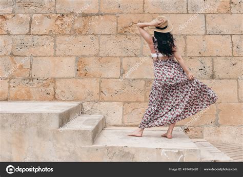 Beautiful Barefoot Brunette Model With Long Dark Hairs Straw Hat And Floral Summer Dress Posing