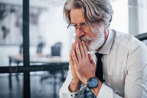 Serious Mature Businessman With Grey Hair And Beard In Formal Clothes Sitting In The Office