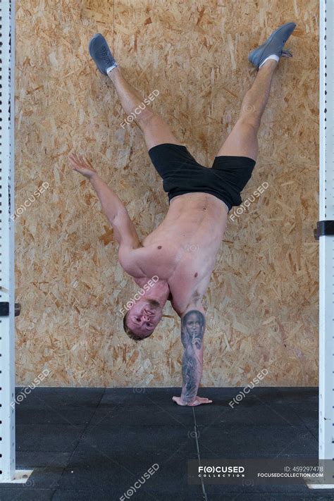 Strong Male Athlete With Naked Torso Balancing On Arm In Handstand While Doing Exercises During