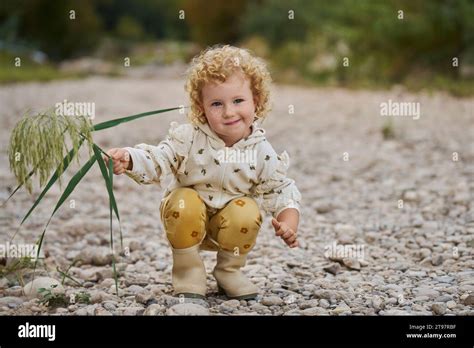 Smiling Cute Girl Crouching With Twig Stock Photo Alamy
