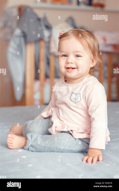 Portrait Of Cute Adorable Caucasian Blonde Smiling Baby Girl With Blue Eyes In Pink Shirt