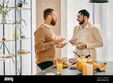 Two Happy Gay Men Chatting In A Modern Kitchen Discussing Breakfast