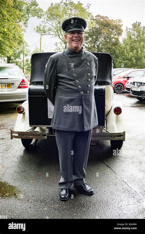 A Chauffeur In Uniform In Front Of Faux Vintage Car Stock Photo Alamy