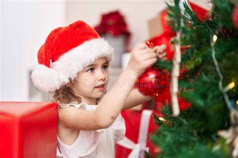 Adorable Caucasian Girl Decorating Christmas Tree At Home Stock Photo