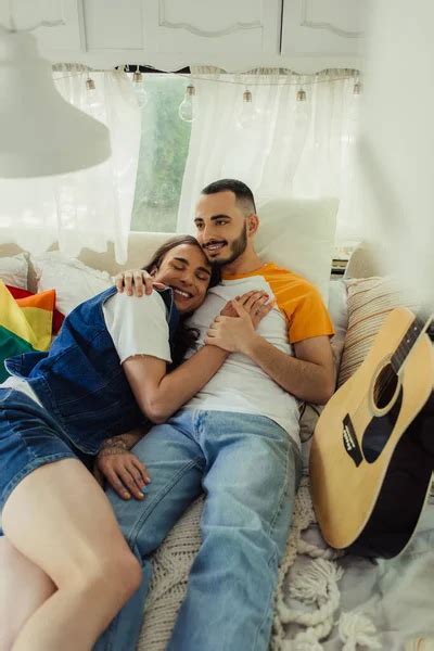Sonriente Gay Hombre Con Tatuaje Acostado En Cama Con Barbudo Novio Cerca Lgbt Bandera En