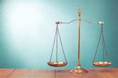 A Golden Balance Scale Sitting On Top Of A Wooden Table Next To A Blue Wall