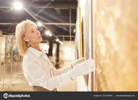 Side View Portrait Elegant Mature Woman Hanging Paintings While Working
