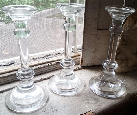 Three Glass Candlesticks Sitting On A Window Sill