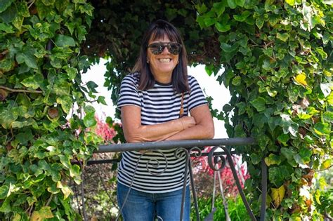 Premium Photo Cheerful Senior Brunette Woman In Denim And Sunglasses Relaxing In The Garden