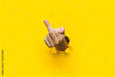 Middle Finger Of Left Hand Insulting Gesture Torn Hole In Yellow Paper Fuck You Concept