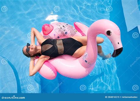 Hot Slim Woman Relaxing On Inflatable Pink Flamingo Float Mattress In Bikini At Swimming Pool