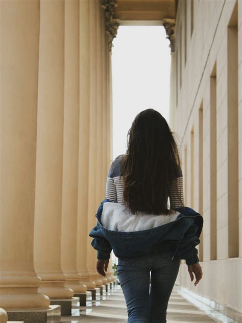 A woman walking down a hallway between two columns photo – Free