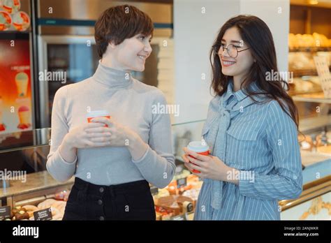 Pretty Blonde Girl Choosing Dessert From Glass Showcase In Bakery Shop Wearing Stylish Beige