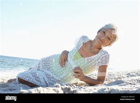 Senior woman laying on tropical beach Stock Photo - Alamy