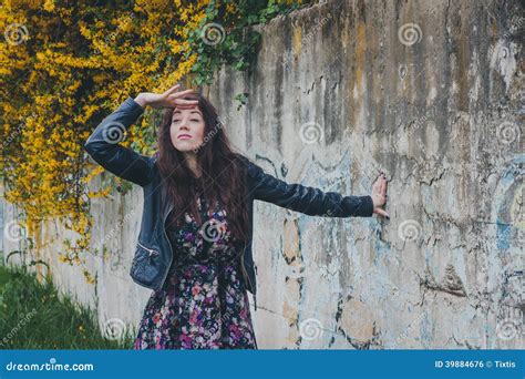 Pretty Girl With Long Hair Leaning Against A Concrete Wall Stock Photo