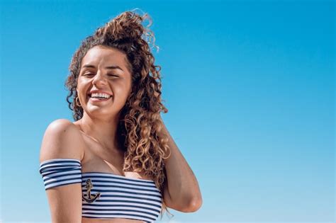 Hermosa joven latina hispana con rizos y en traje de baño en la playa feliz y sonriente imagen