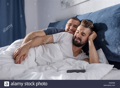 Happy Gay Couple Lying Together In Bed And Holding Hands Stock Photo Alamy