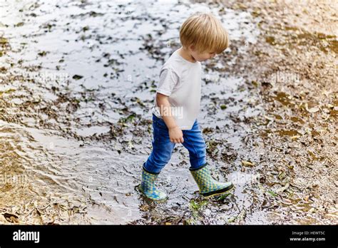 Boy Wearing Rubber Boots Playing In Muddy Puddle Stock Photo Alamy