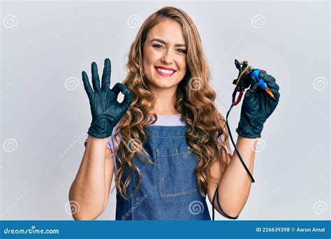 Jeune Fille Blonde Tenant Machine De Tatouage Faire Ok Signe Avec Les Doigts Sourire Amical