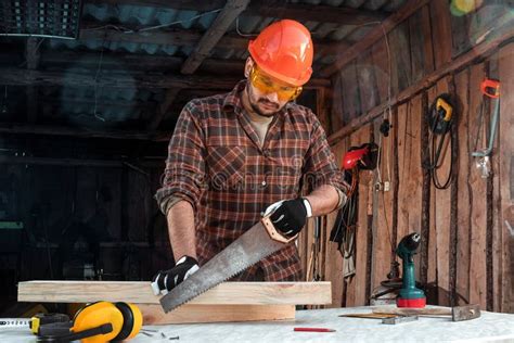 A Man Carpenter Cuts A Wooden Beam Using An Electric Jigsaw Male Hands