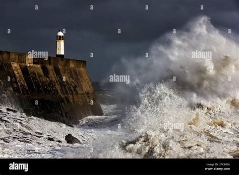 Coastal Town Seafront And Lighthouse Bombarded By Waves In Storm