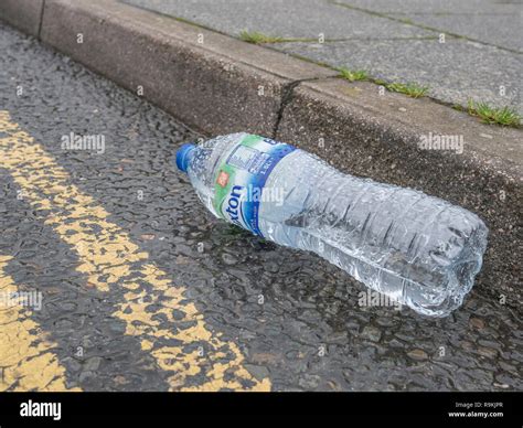 Empty PTFE plastic mineral water bottle discarded in urban road gutter ...