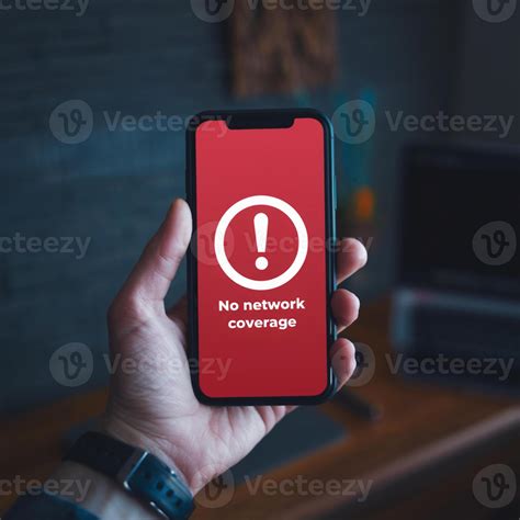 Hand holds smartphone with No Network alert on red screen against dark ...