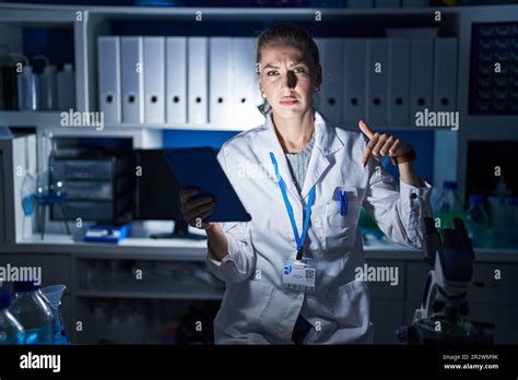Beautiful Blonde Woman Working At Scientist Laboratory Late At Night Pointing Down Looking Sad