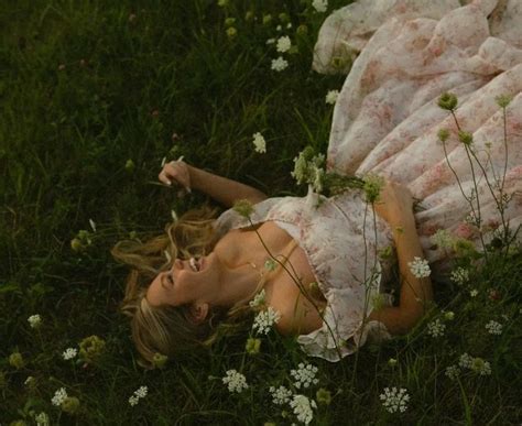 A Woman Laying In The Grass With Flowers