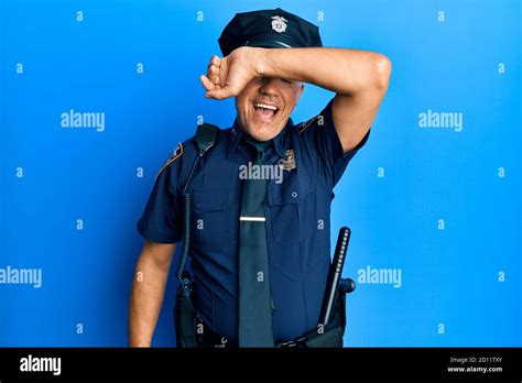 Handsome Middle Age Mature Man Wearing Police Uniform Covering Eyes With Arm Smiling Cheerful