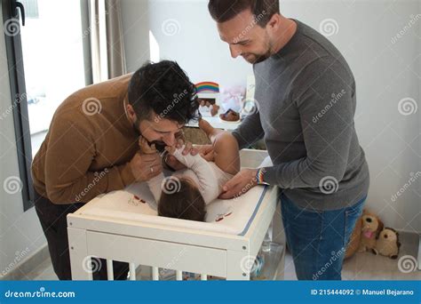 Gay Married Couple Changing Their Daughter S Diaper In The Bedroom Stock Photo Image Of