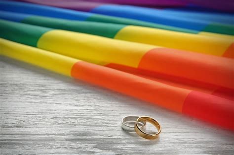 Dos Anillos De Boda Y La Bandera Gay Del Arco Iris Sobre Fondo De Madera Foto Premium
