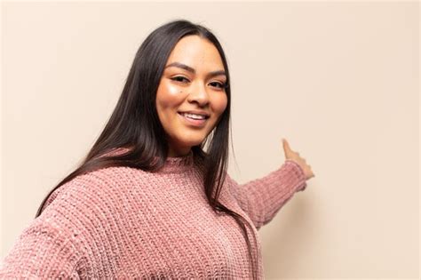 Joven latina que se siente feliz y alegre sonriendo y dándote la bienvenida invitándote con un
