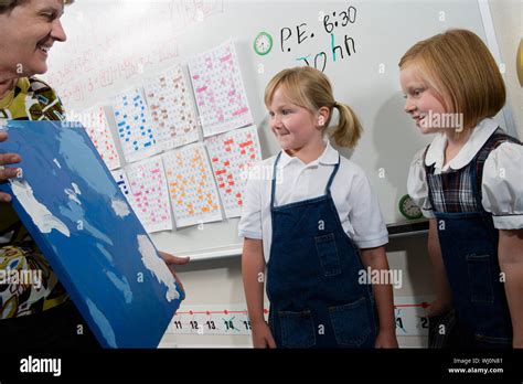 Mature Teacher Showing Her Art To Female Students In Classroom Stock Photo Alamy