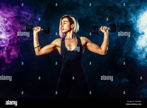 Attractive Sporty Blonde Woman In Fashionable Sportswear Does The Exercises With Dumbbells