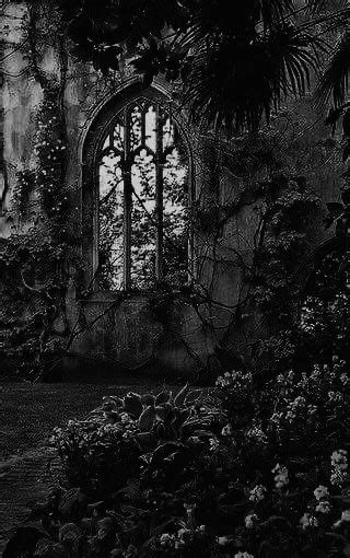 A Black And White Photo Of An Old Building With Flowers Growing In The