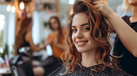 Premium Photo A Woman With Long Curly Hair Smiles At The Camera As A Stylist Works On Her Hair