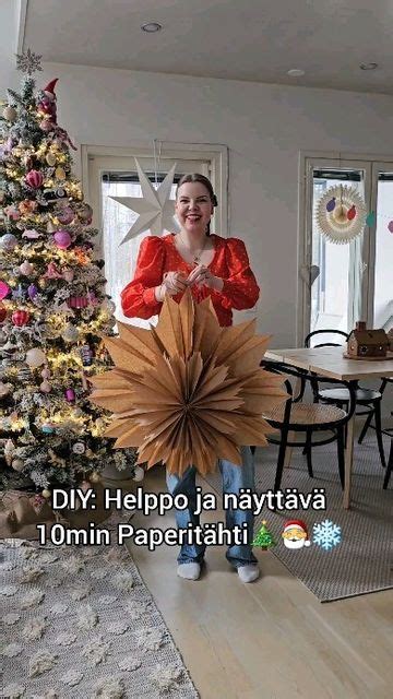 A Woman Standing In Front Of A Christmas Tree Holding A Giant Paper