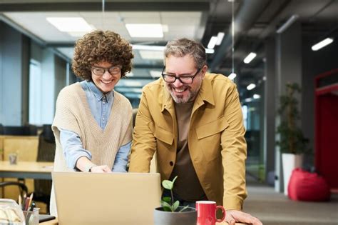 Heureuse Jeune Femme Et Son Coll Gue Masculin Mature Regardant Un Cran D Ordinateur Portable