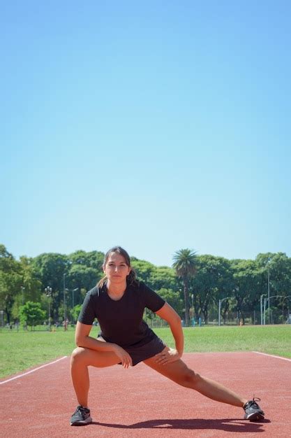 Imagem Vertical De Uma Jovem Corredora Latina Na Pista Esticando As Pernas E O Quadril Foto