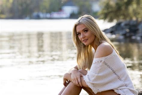 A Lovely Blonde Bikini Model Poses Outdoors Near A Lake While Enjoying The Summer Weather Stock