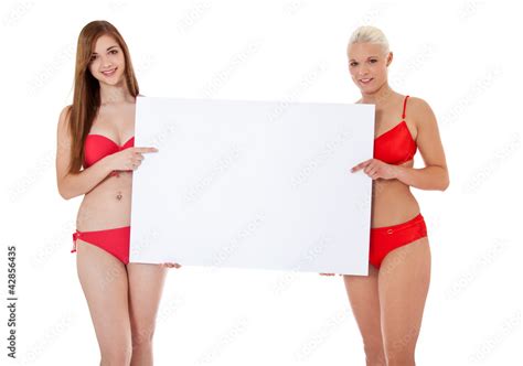 Zwei attraktive junge Frauen im Bikini hinter weißem Schild Stock Photo Adobe Stock