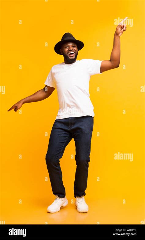 Cheerful black man dancing and pointing index fingers aside Stock Photo ...