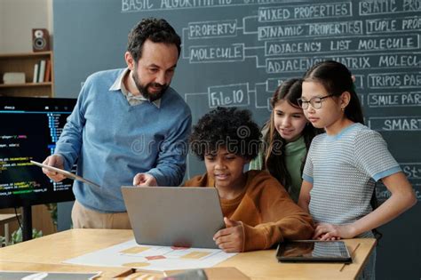 teacher engaging students coding lesson laptops stock