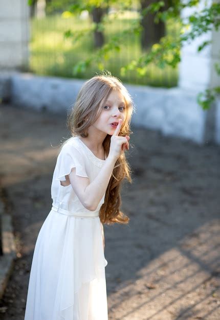 Premium Photo A Beautiful Girl With Long Blonde Hair 8 Years Old Stands In A White Silk Dress