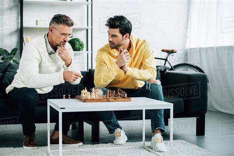 Pensive Son And Mature Father Playing Chess Together On Weekend At Home Stock Photo Dissolve